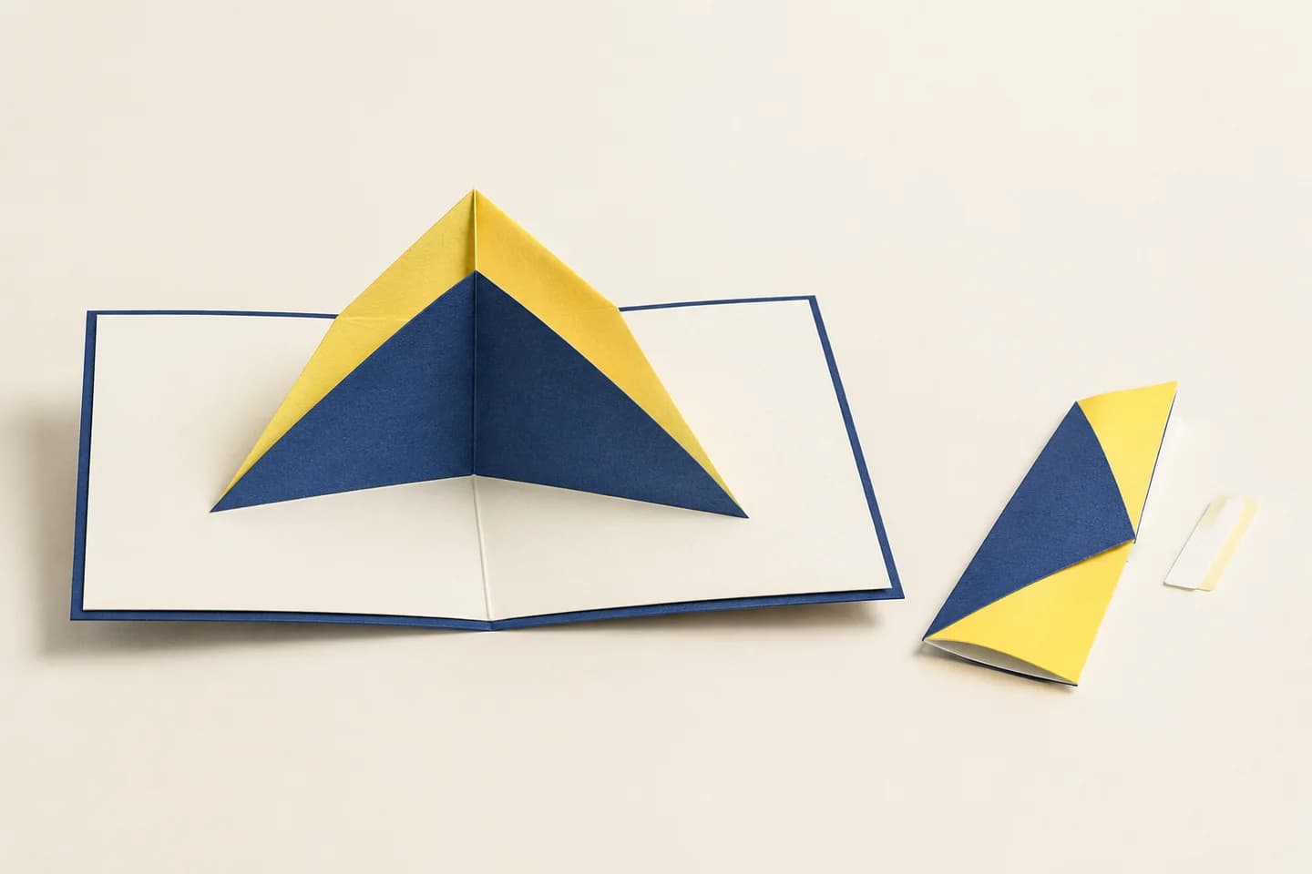 Paper-engineered V-fold spread with a separate folded component and attachment tab