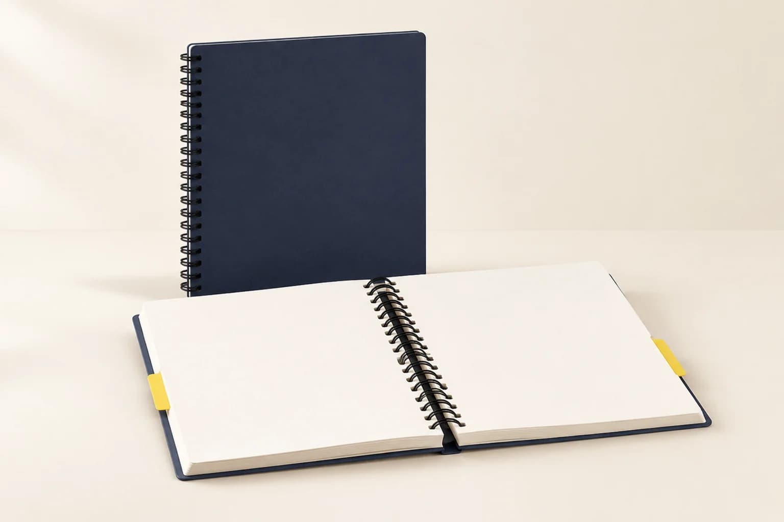 Illustrative closed navy spiral-bound book beside an open coil-bound workbook with yellow divider tabs