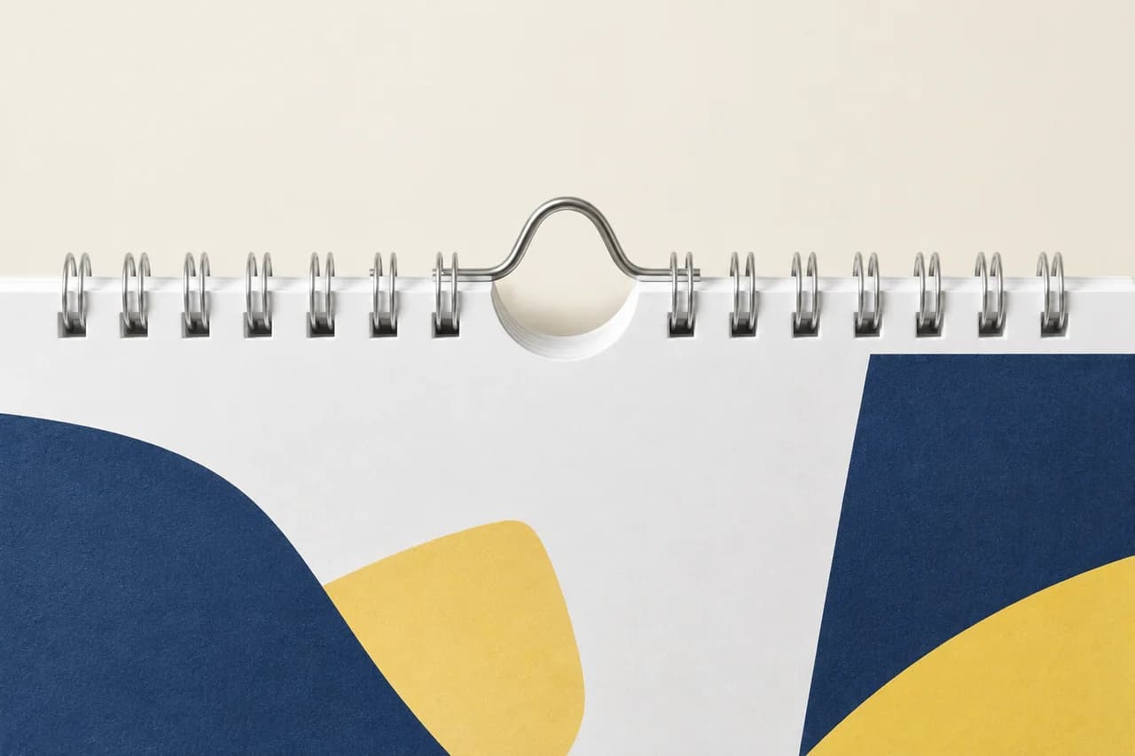 Close-up of twin-loop calendar binding with a central hanger and thumb cut